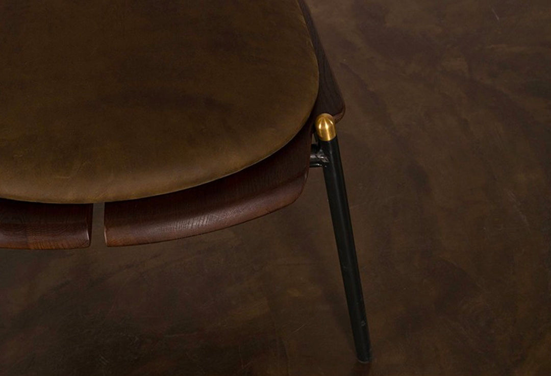 Leather seat with metal frame on dining chair on brown floor.