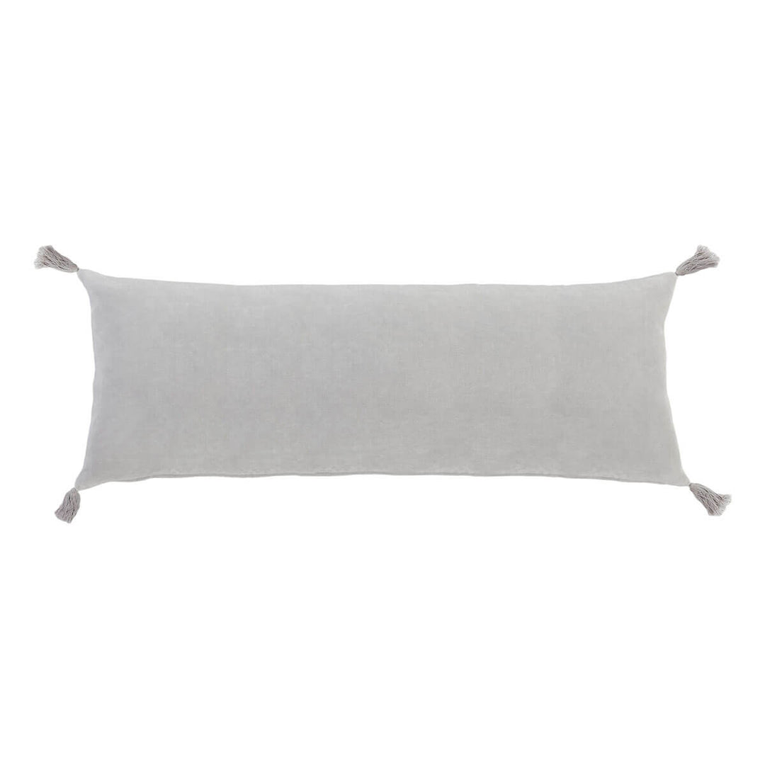The Banjul Pillow - Light Grey is a light grey velvet rectangular pillow with tassels in the corner.