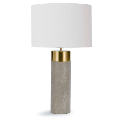 The Belo Table Lamp features a fabric shade atop a brushed brass column base. 