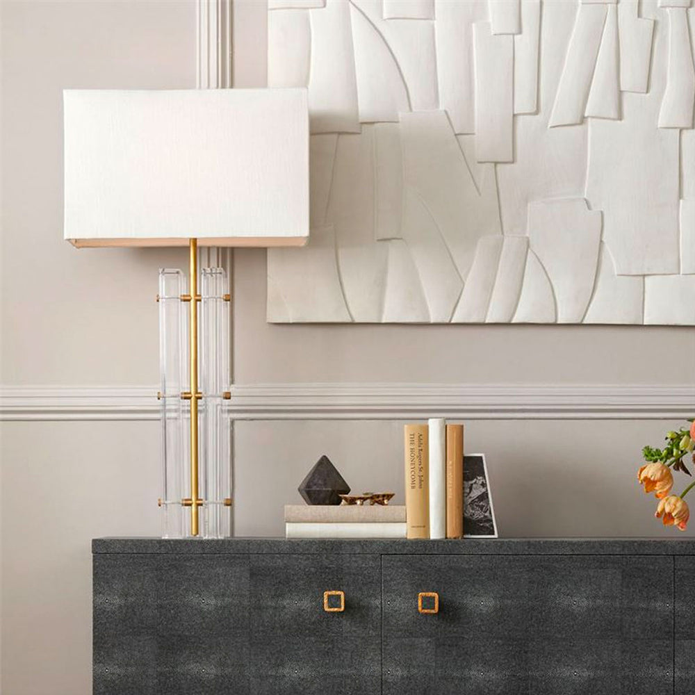 Lifestyle image of console table with lamp, books, flower, and concrete artwork above.