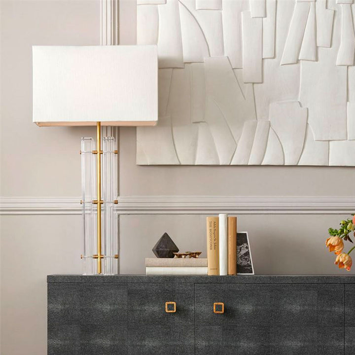 Lifestyle image of console table with lamp, books, flower, and concrete artwork above.