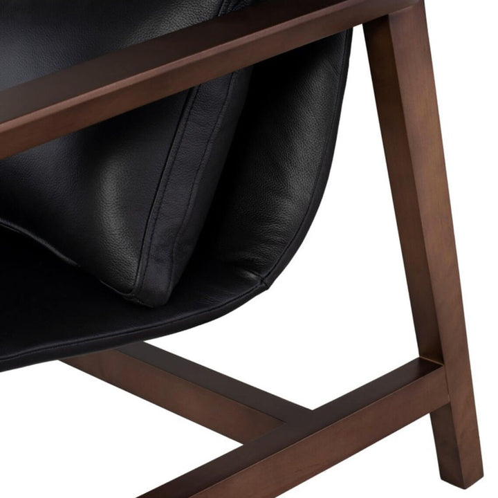 Closeup of the solid wood legs in a rich walnut finish and the black leather seat.