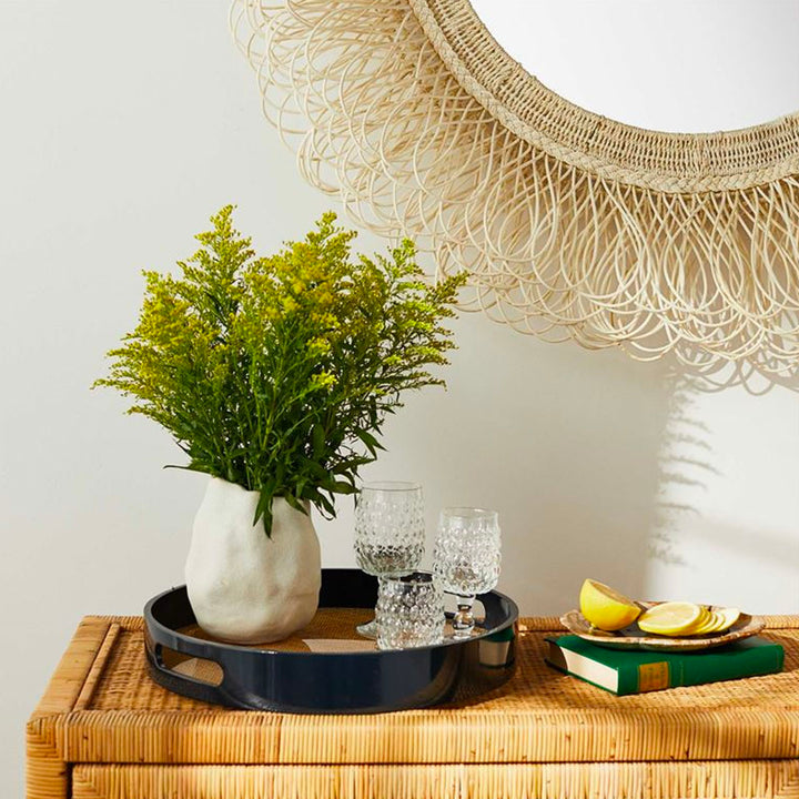 Glossy, round tray with greenery, styled on a console table with a mirror above.