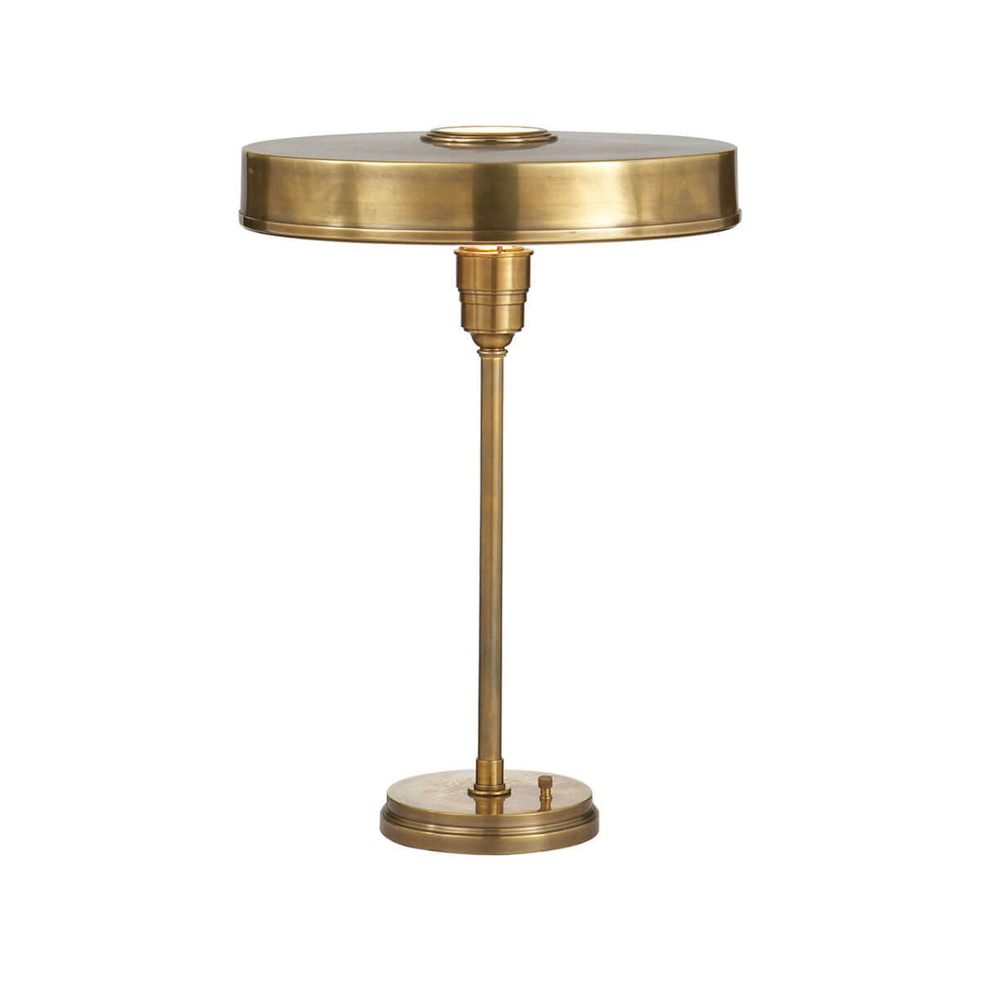 The Carlo Table Lamp is a classic metal desk lamp with a hand-rubbed antique brass finish and a flat, round shade.