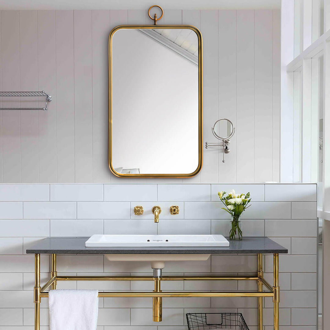 Small brass bathroom mirror over a sink.