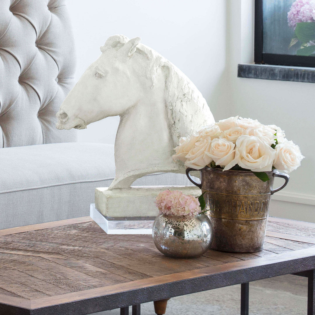 Coffee table with pink flowers and traditional horse head sculpture.