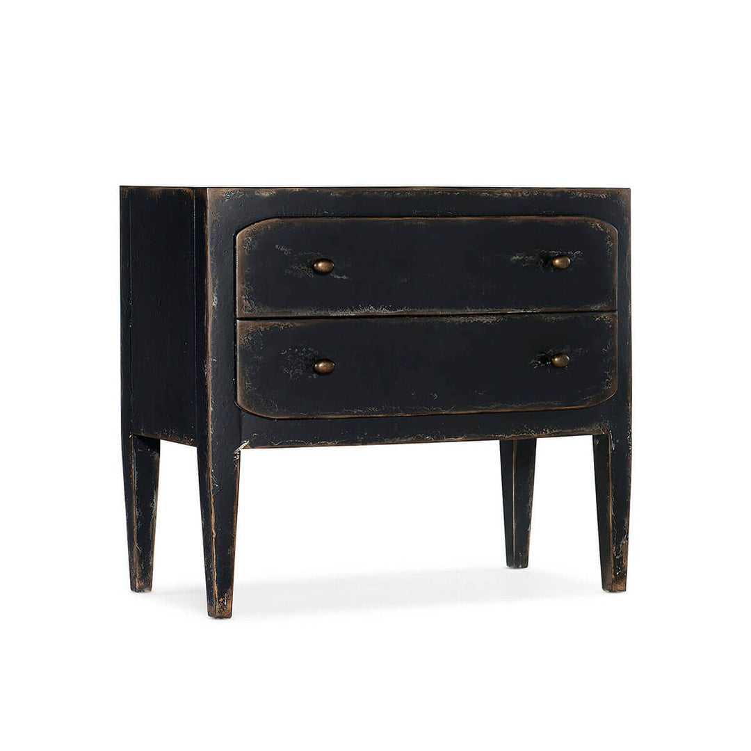 The Estoril Nightstand is a black, distressed two drawer dresser with burnished brass hardware and a modern farmhouse look.