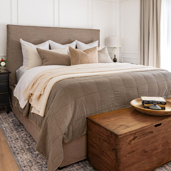 Feminine bedroom styled with neutral toned bedding and upholstered bed.