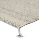 Close up of carpet edging on the Flora Rug in the colour grey/ivory. This rug features braided tassels in each corner.