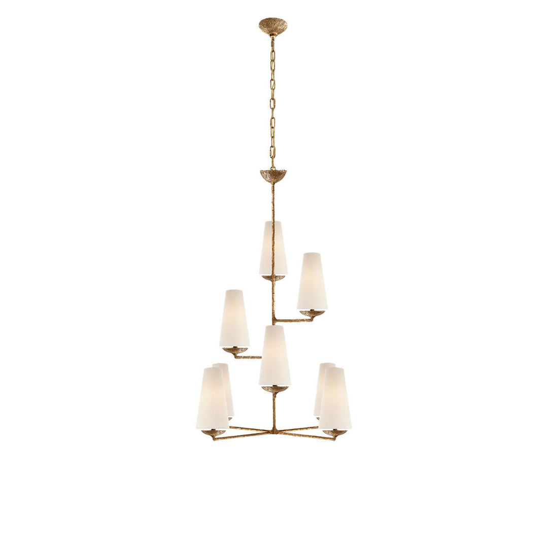 The Fontaine Vertical Chandelier is a high-ceiling chandelier with eight staggered, vertical lights with linen lamp shades and a gilded plaster stem.