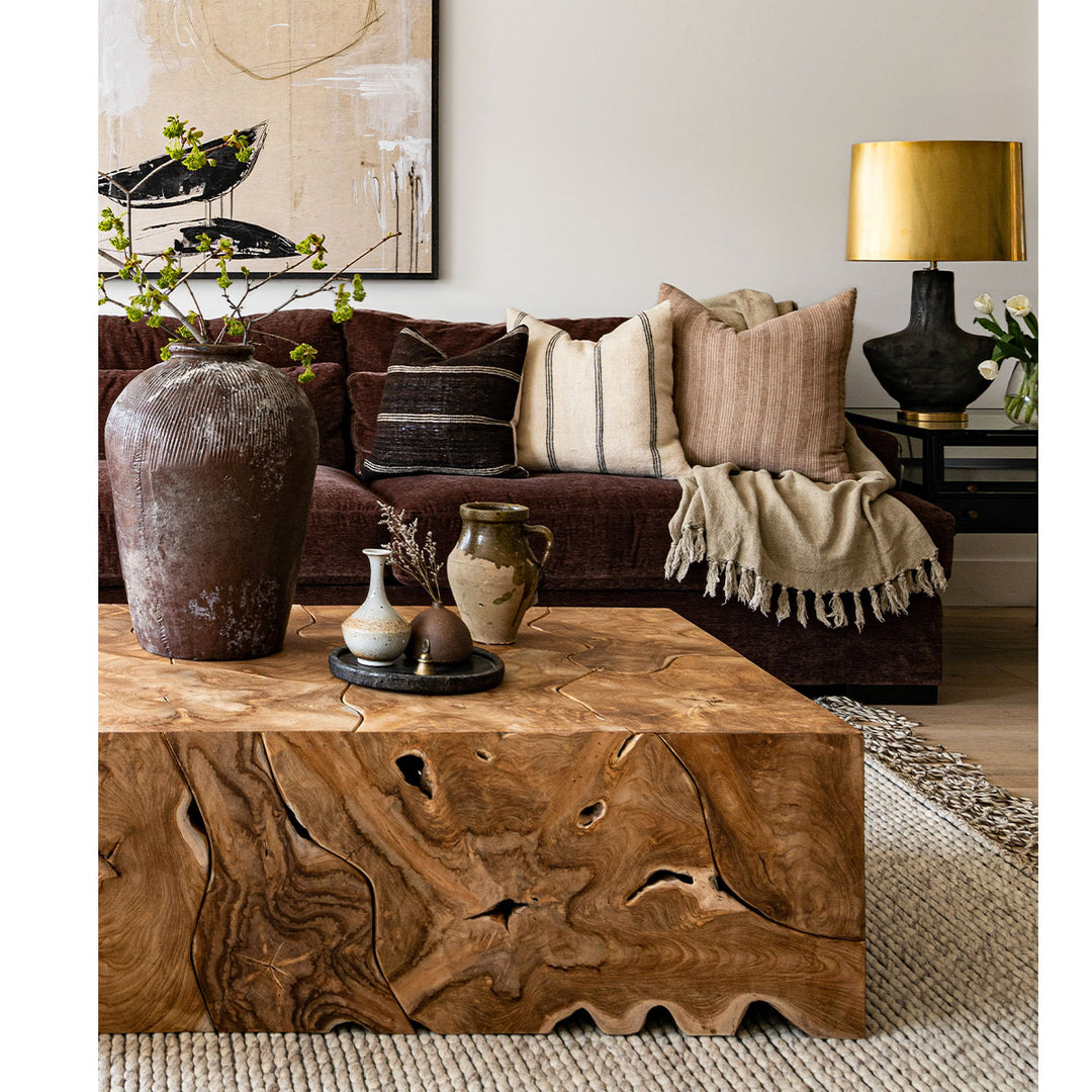 Natural and rustic toned living room featuring a raw wood coffee table, vintage pottery and maroon coloured sofa.