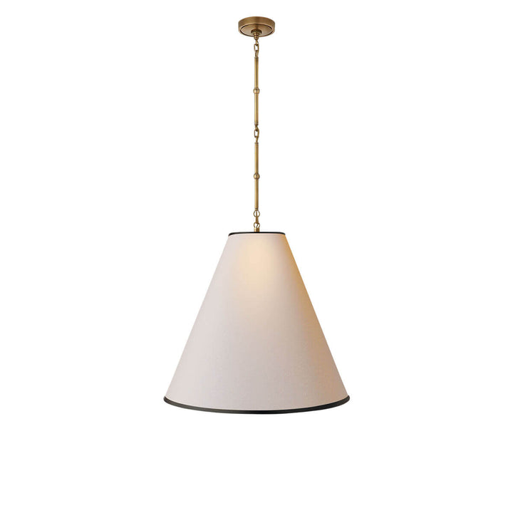 The Goodman Hanging Lamp has a delicate, hand-rubbed antique brass chain with a natural paper, cone shaped shade with a black trim.