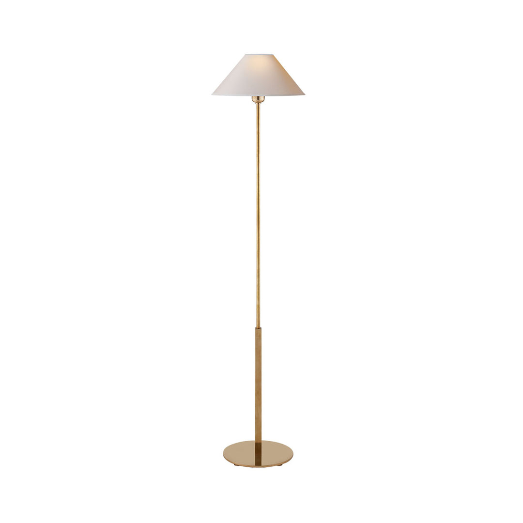 The Hackney Floor Lamp has a thin body in a hand-rubbed antique brass finish and a round, natural paper lamp shade.