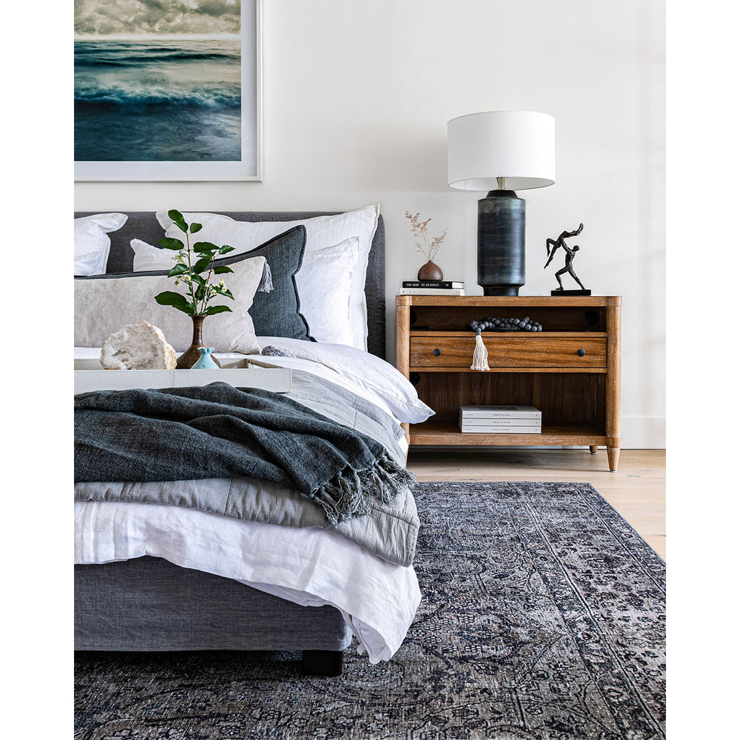 Grey, blue and white toned, mature themed bedroom with antique rug, upholstered bed frame, and decorative accessories.