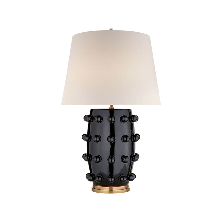The Linden Table Lamp is a statement lamp with a black porcelain base with ball details and an off white linen shade.