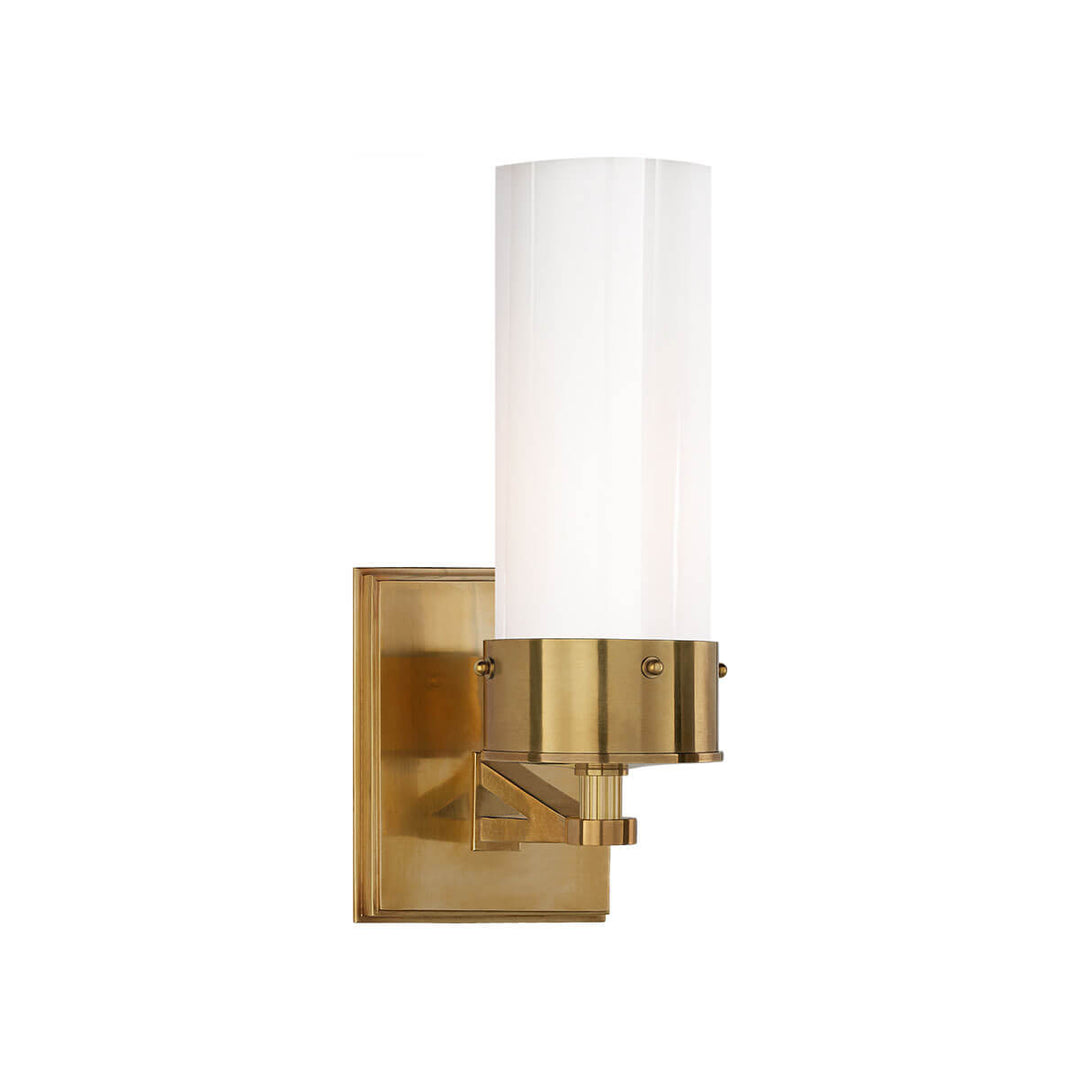 The Marais Wall Sconce has a hand-rubbed antique brass square backplate and covered bolts and a white glass cylindrical shade.