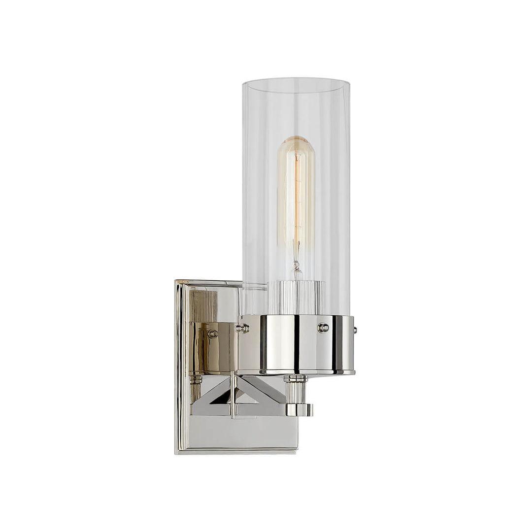 The Marais Wall Sconce has a polished nickel square backplate and covered bolts and a clear glass cylindrical shade.