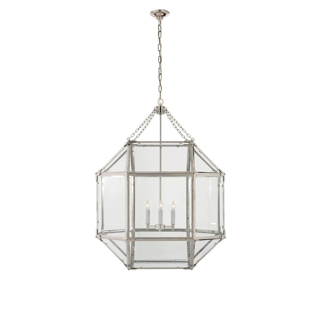 The Bruggen Large Lantern has three candelabra lights in the middle of a polished nickel cage-like frame with visible joints and clear glass panels.