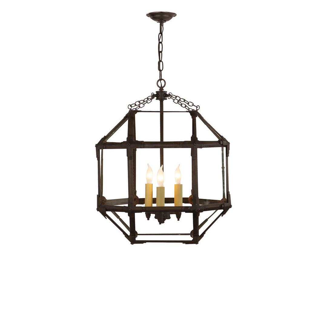 The Morris Medium Lantern has three candelabra lights in the middle of an antique zinc cage-like frame with visible joints and clear glass panels.