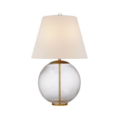 The Morton Table Lamp has a round, clear glass base with a brass stem running thought it and a tapered, linen shade.