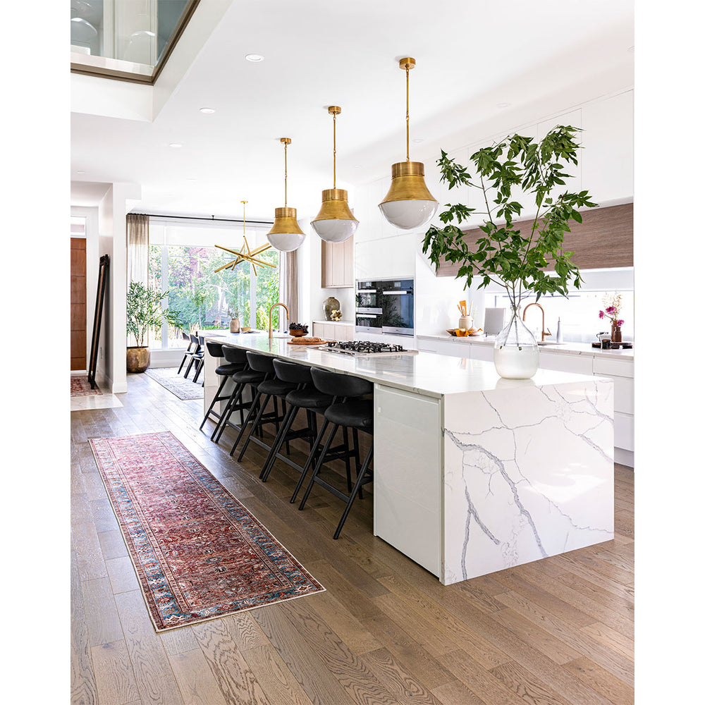 A modern and bright kitchen with a large island and antique brass large pendants featured above.