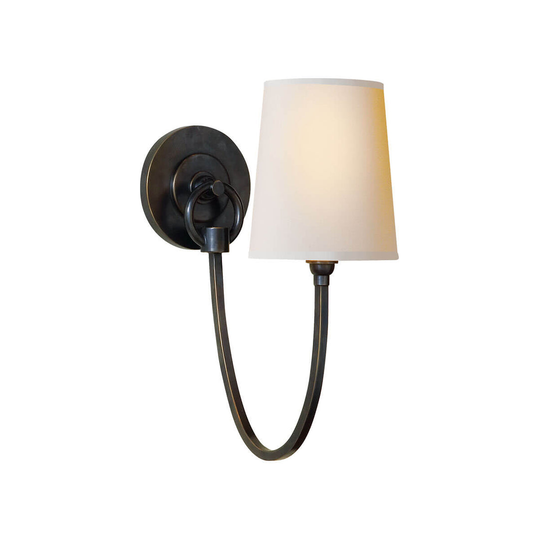 The Reed Wall Sconce has a natural paper shade and a bronze hooked arm and round backplate.