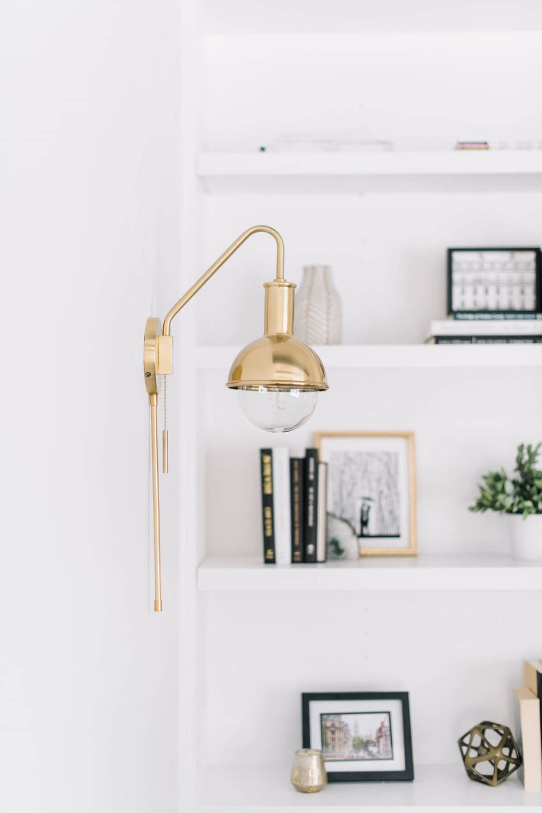Aged brass wall sconce with adjustable arm in a white living room.