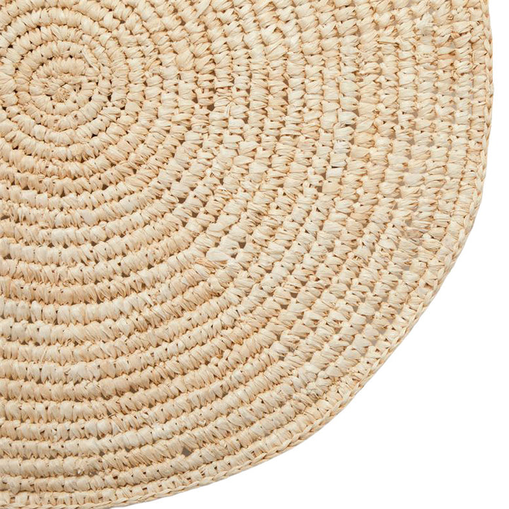 Closeup of a woven, round piece of natural wall art.