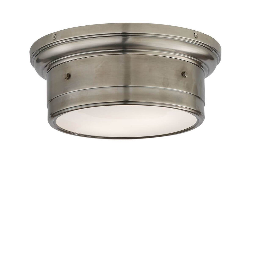 The Siena Flush Mount has a simple drum shape in a antique nickel finish with covered bolt details and a white glass diffuser