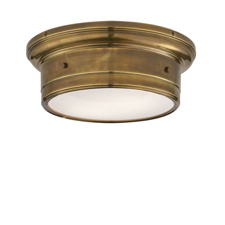 The Siena Flush Mount has a simple drum shape in a hand-rubbed antique brass finish with covered bolt details and a white glass diffuser