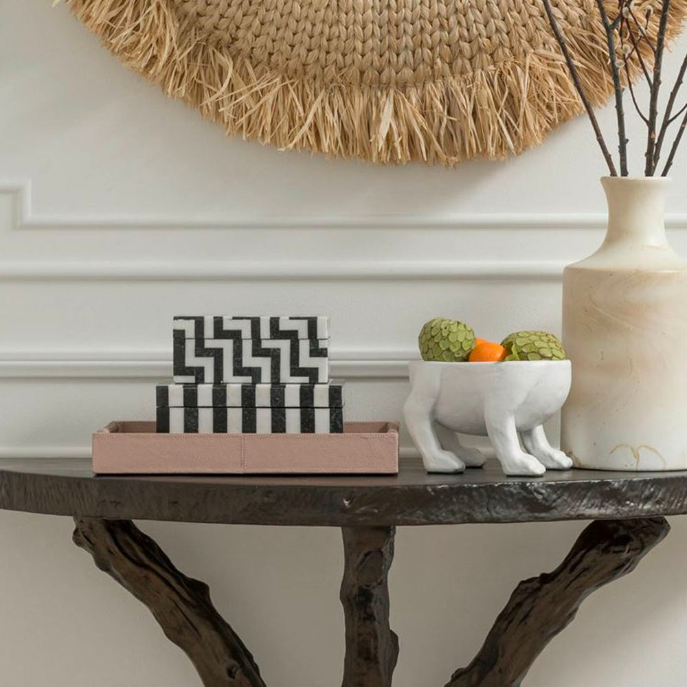 Pink leather tray on a console table styled with greenery, pottery, and art.