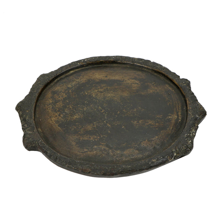 Black, hand-carved stone plate with ornate details.