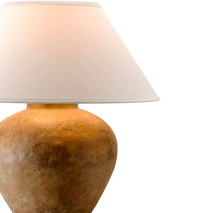 Close up image of small table lamp with terracotta coloured base and linen shade.