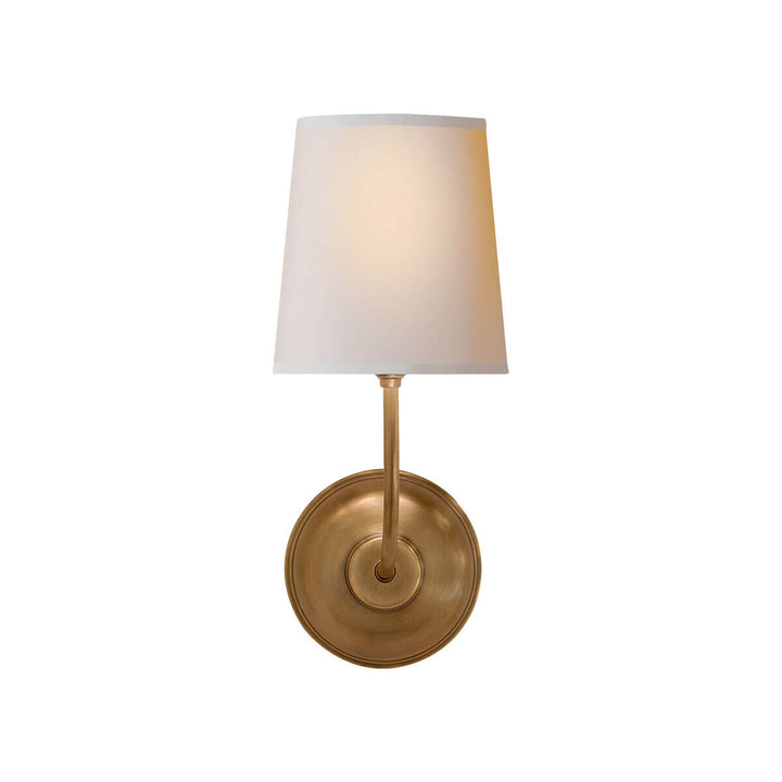 The Vendome Single Wall Sconce has a single natural paper shade with a round backplate and simple, curved arm in a hand-rubbed antique brass finish.
