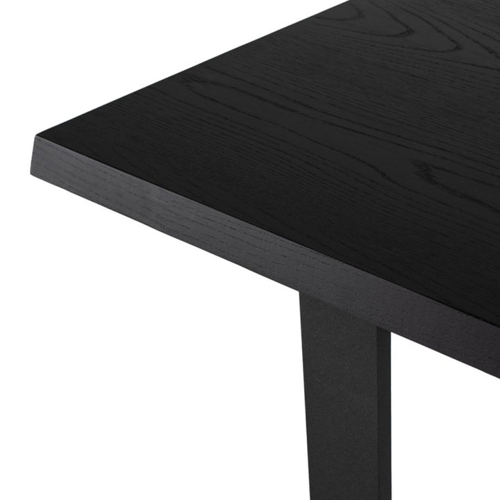 Black onyx wood veneer tabletop and matte black steel leg details on a modern dining table.