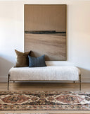A neutral piece of artwork depicting a sandy beach in neutral colours with a modern, coastal vibe. Hanging in a cozy living room with a styled console and vintage accesories.